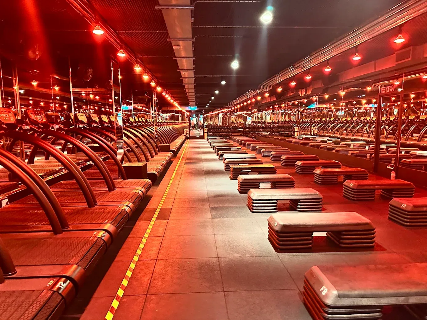 The red room at Barry's Bootcamp Queensway — empty studio before class with treadmills and benches under signature red lighting