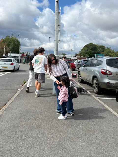 Tanvi e Tarini, com tops de listras combinadas, no estacionamento dos postos de serviço da estrada a caminho de Bath.