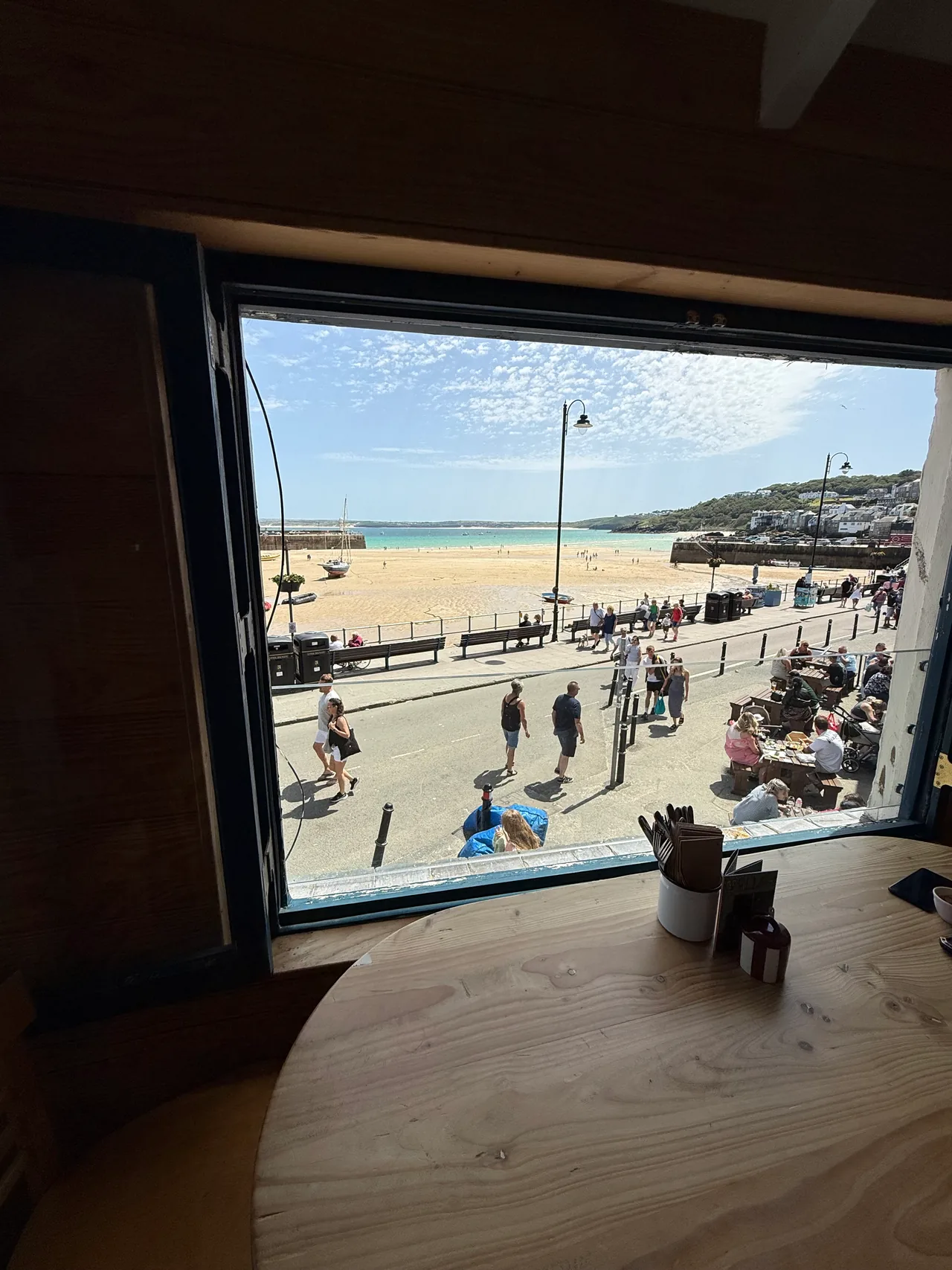 The seafront at St Ives seen from a cafe window, with the beach, promenade and bay beyond.