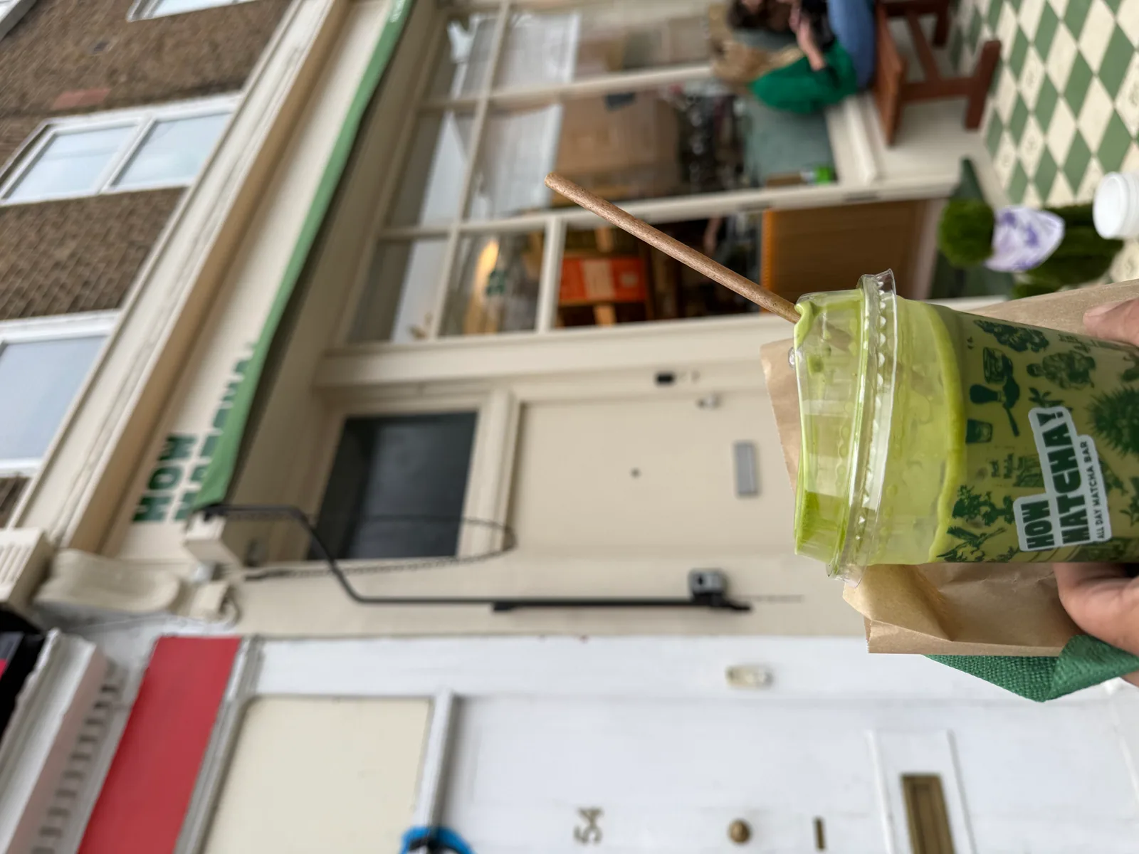 A bowl of bright green matcha latte on a wooden counter at HowMatcha Notting Hill
