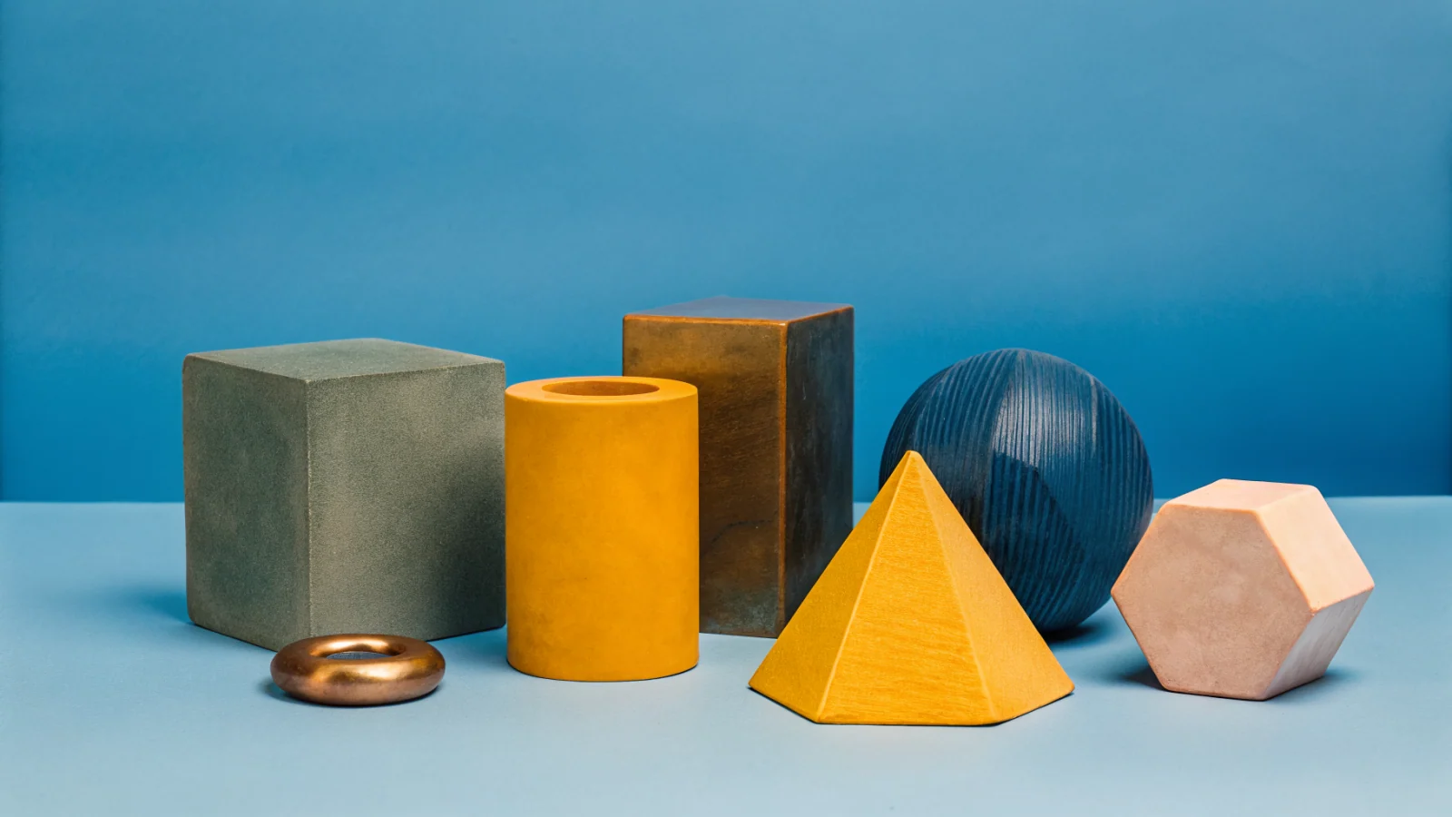 A clean shelf with eight distinct geometric tools arranged in a precise row, suggesting a curated production stack