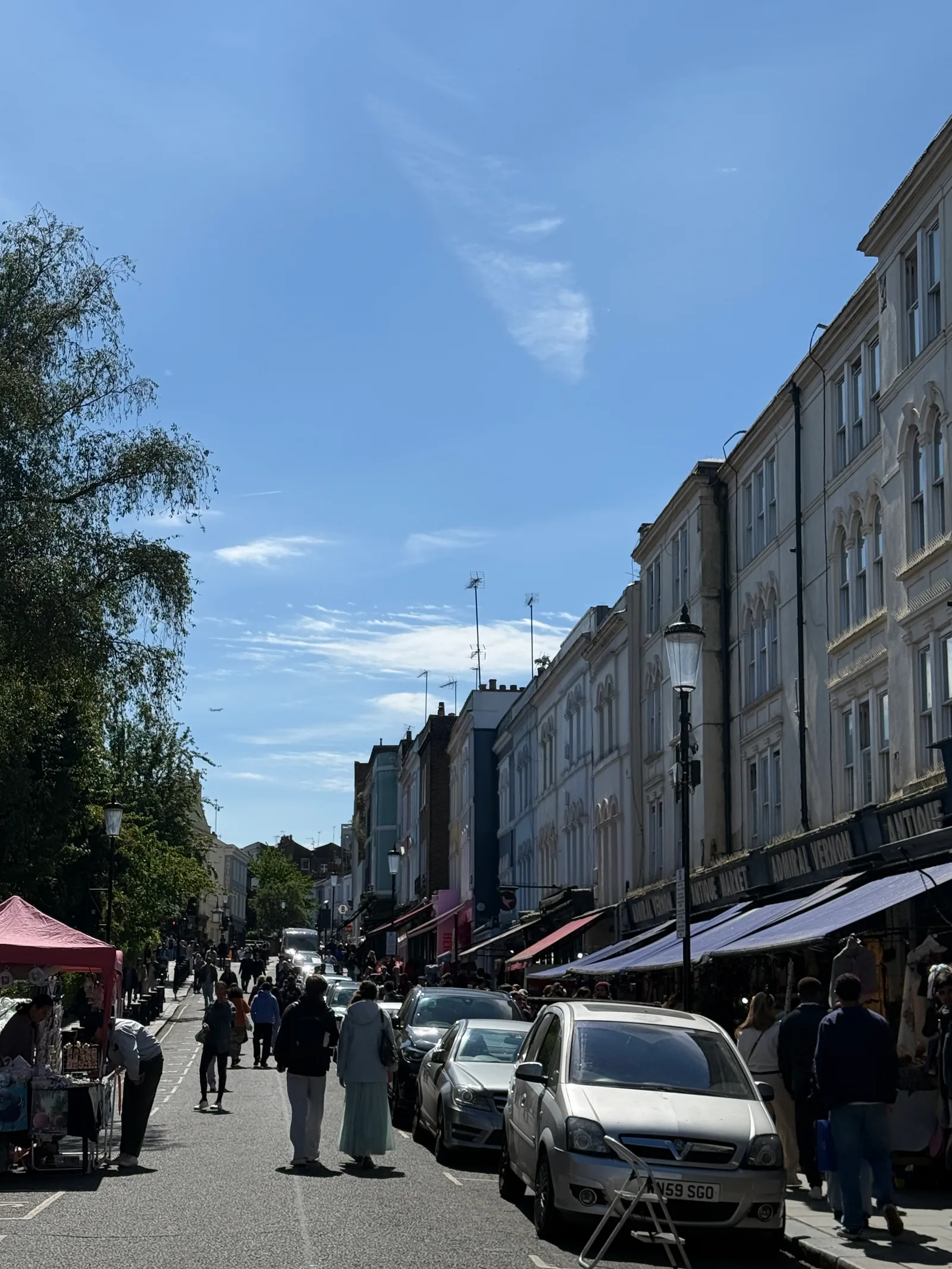Portobello Road in Notting Hill on a bright sunny day, looking south toward the antiques market with the white stuccoed terraces of W11